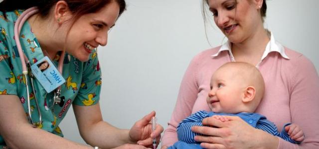 Nurse vaccinates smiling baby.